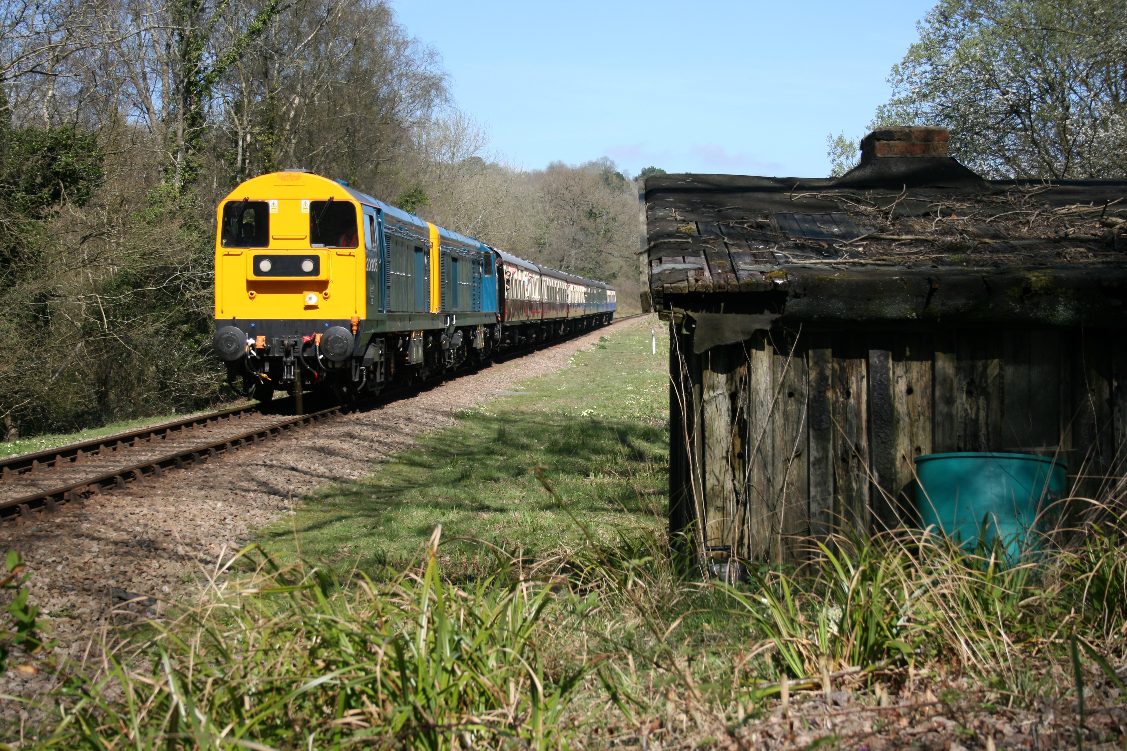 Railway tracks with yellow train and wooden shack