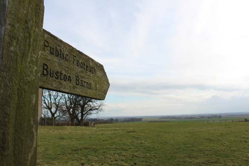 Second wooden signpost, marked Buston Barns, pointing toward footpath on the Alnmouth Circular Walk.