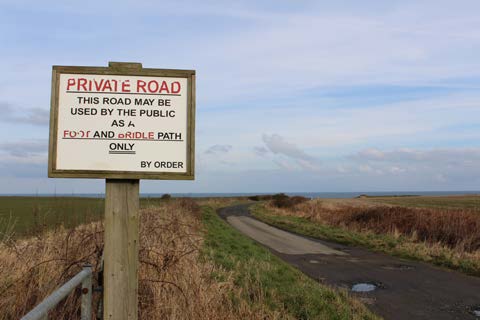 Wooden sign highlighting a private road and public footpath on the Alnmouth Circular Walk.