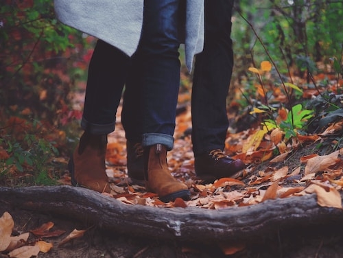 A close up of two people's legs walking through the woods