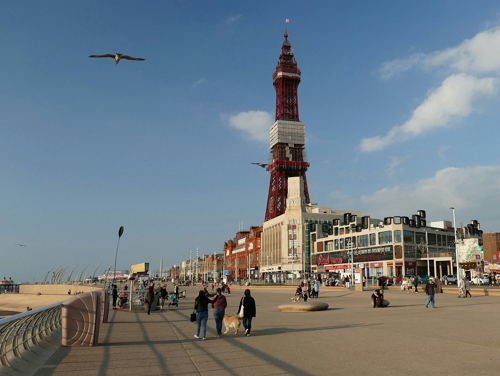 Blackpool pleasure beach on a sunny day with crowds of people.