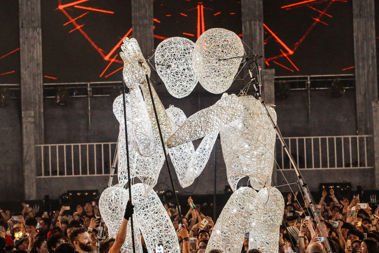 Two human shaped light figures touching hands.