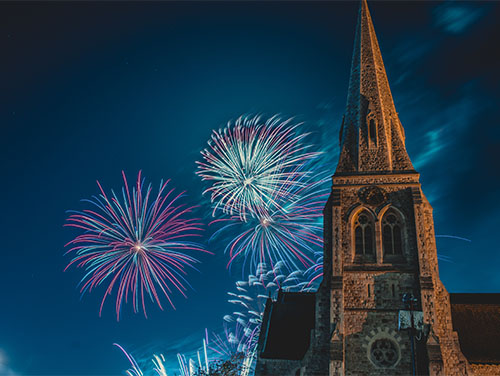 Fireworks exploding in the sky beside a church