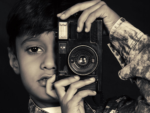 A child holding a vintage camera.