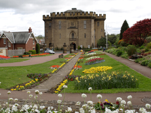 A house in Carlisle Park that is surrounded by neatly maintained garden beds of flowers.