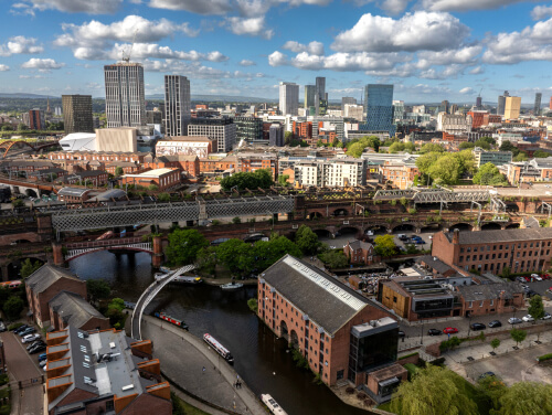 Aerial view of Manchester’s Castlefield district, showing historic railway viaducts, canals, red-brick buildings and the modern city skyline.