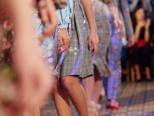 Models walking a runway in grey floral outfits.