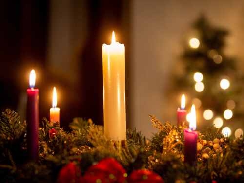 Christmas candles and fern in a dimly lit room.