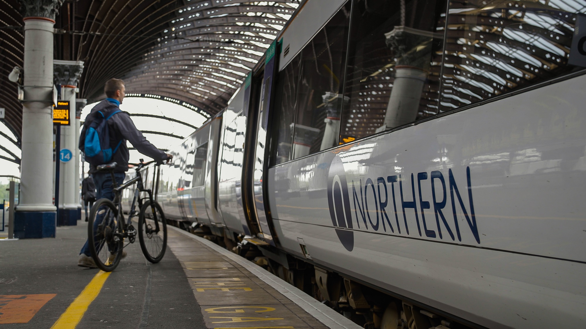 Person getting on a Northern train with a bike