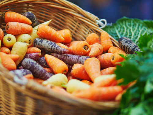 Basket of colourful carrots and leafy vegetables.