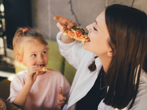 A mother and daughter enjoying slices of pizza.
