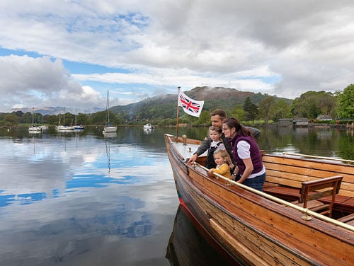 Family of four on a wooden boat on the Lake District water