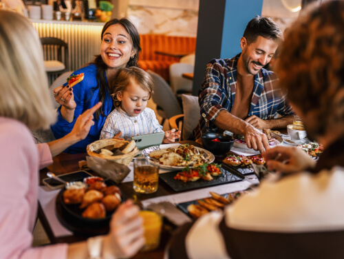 Family and friends sharing a meal together at a restaurant, with a young child at the table.