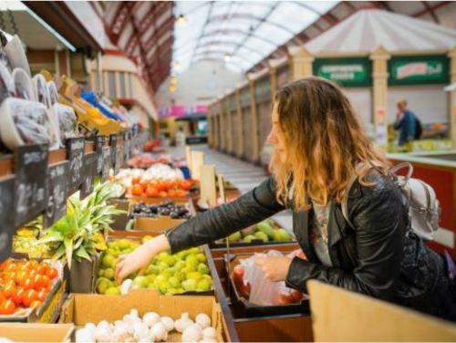 A woman selecting fresh fruit at an indoor market stall.