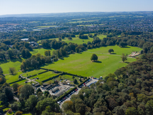 A grassy park from above, there is a carpark in the park too.