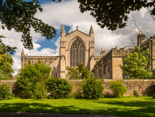 the facade of hexham abbey in the sunshine with it's impressive stained glass windows on display.