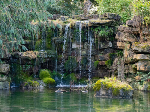 Small waterfall flowing over rocks into a pond.