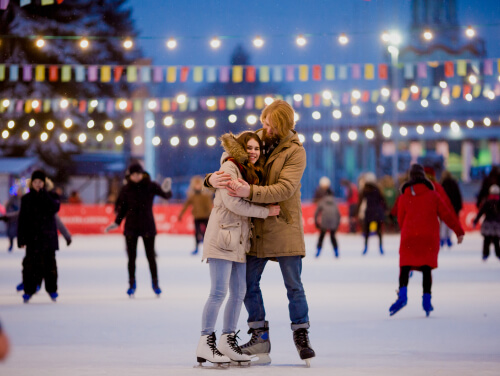 A mother hugging her daughter on the ice rink as people skate behind and around them.