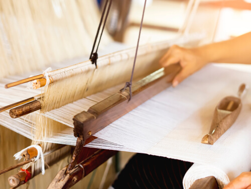 A pair of hands using a silk weaving machine