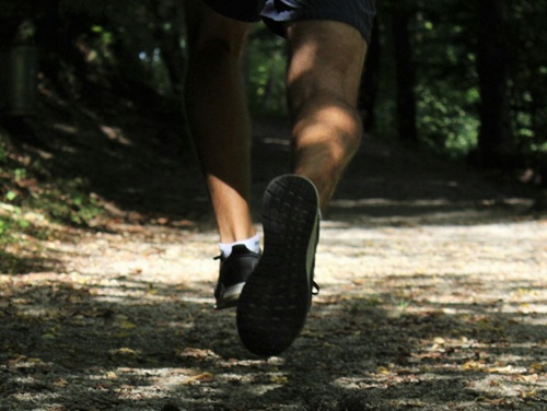 A close-up of the back of a runner's legs going through a forest