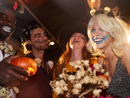 Friends in Halloween costumes laugh together at a party.
