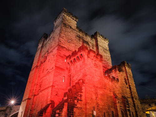 Newcastle Castle illuminated by red light at night