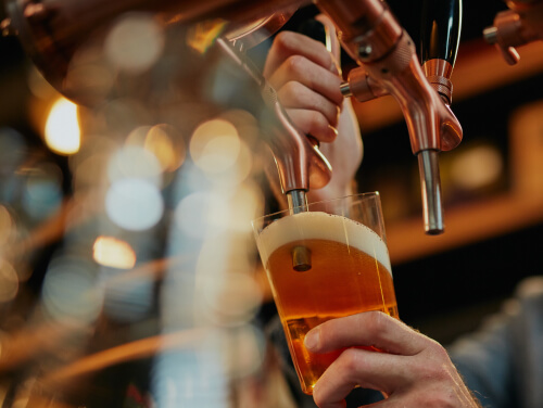 A bartender pouring a beer in a bar from a tap.