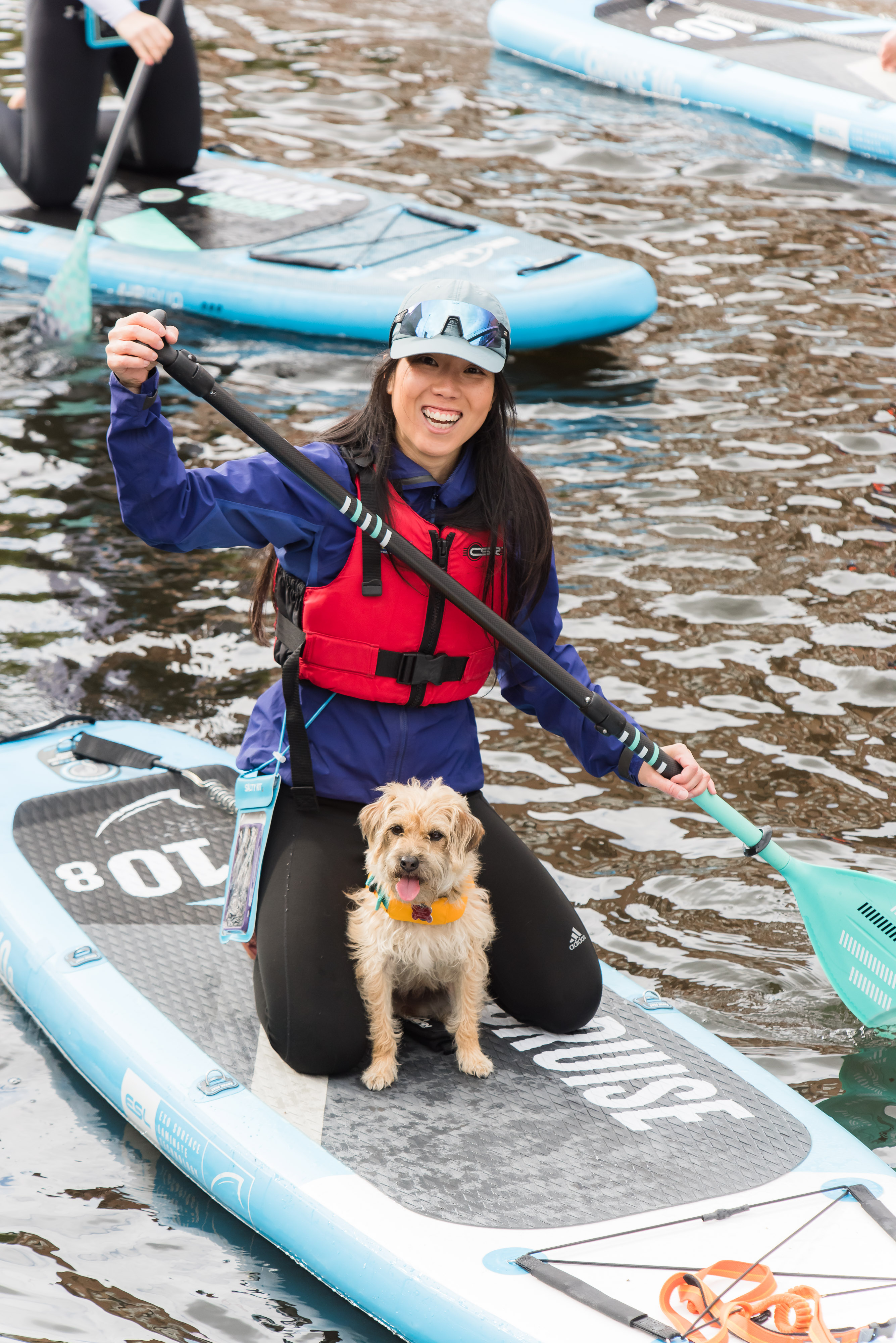 Image of a woman paddleboarding with her dog