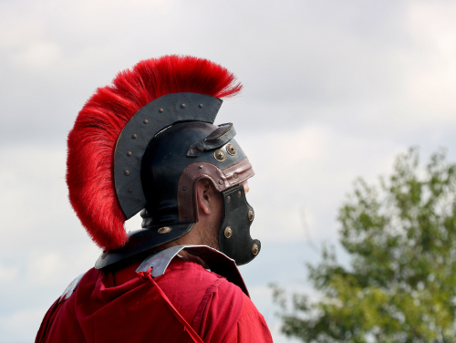 Man dressed in traditional red Roman costume with his back to the camera