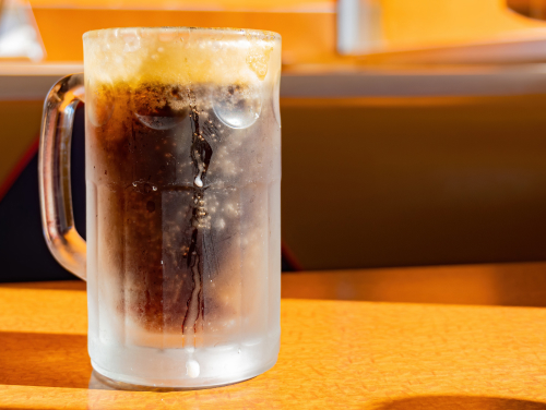 An ice cold glass of root beer, dripping with condensation. 