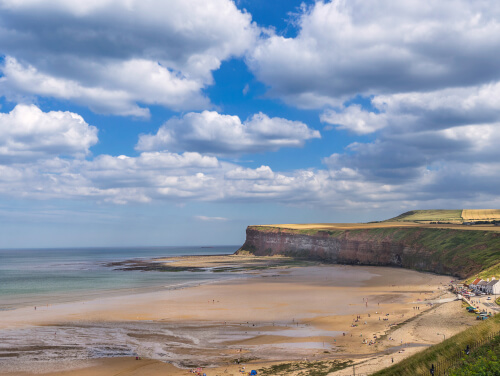 Saltburn beach while the tide is out showing a large portion of the sandy shore.