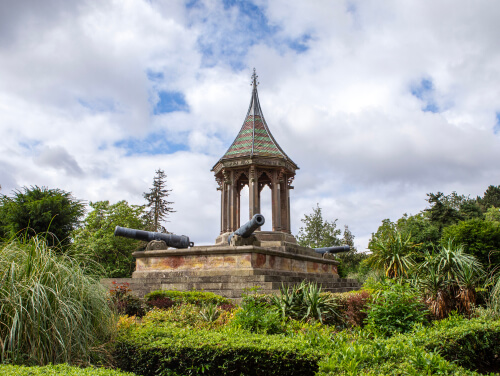 Garden monument with cannons surrounded by greenery.