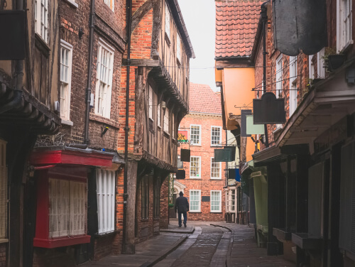 The narrow medieval Shambles in York, lined with timber-framed buildings and warm brickwork, creating an atmospheric setting for an October city break.