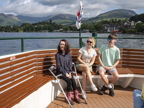 A group of friends sitting on a bench surrounded by views of Cumbria and the Lake District.