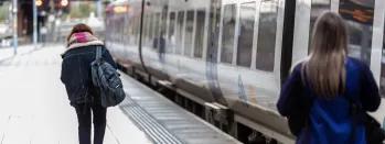 Image shows customer boarding a train as conductor looks on image-shows-customer-boarding-a-train-as-conductor-looks-on