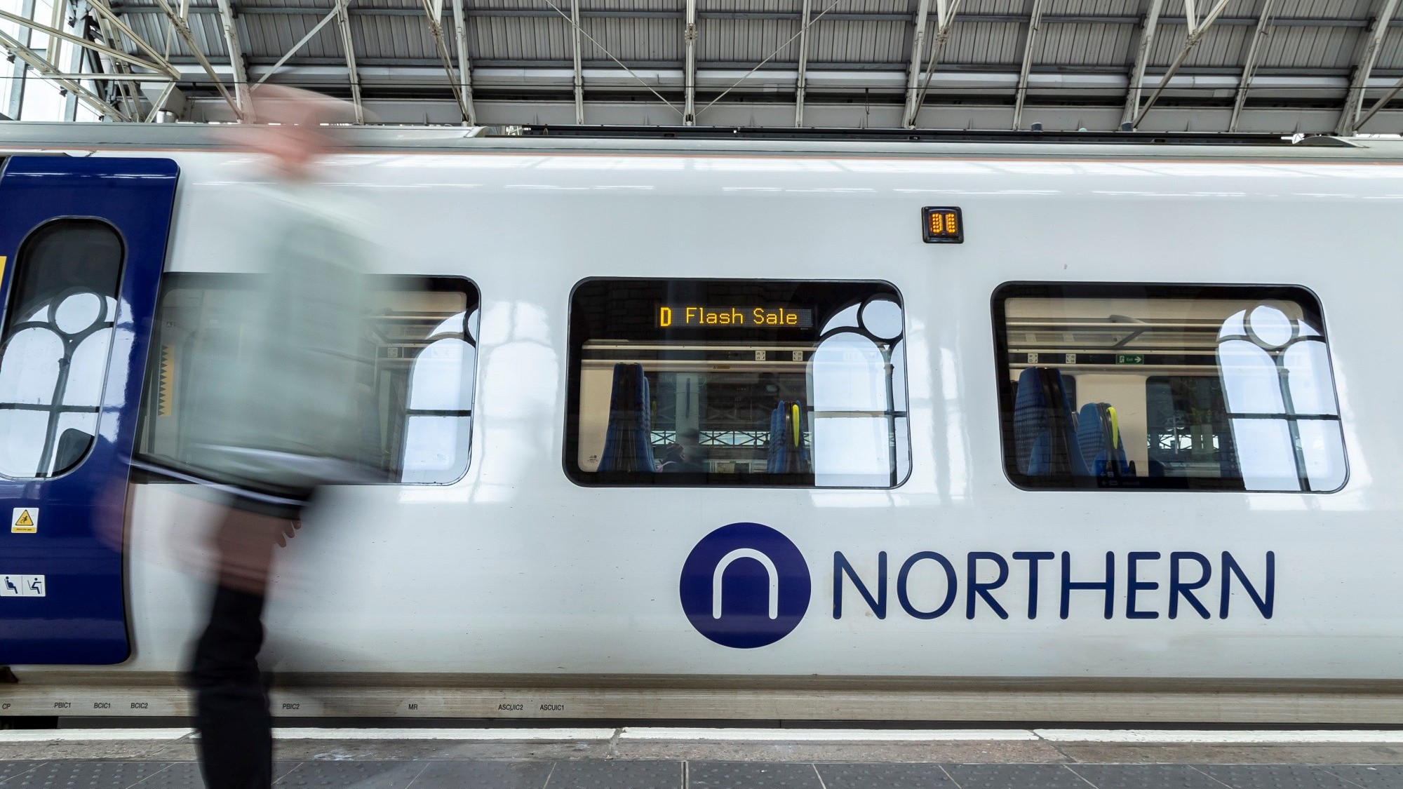 Image shows passenger alongside Flash Sale branded Northern train